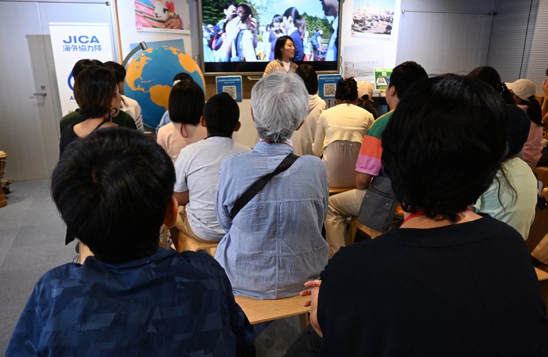 JICAの施設で開かれた「こども冒険バンク」で、ウガンダに赴任した経歴を持つ兼本友希さんの話を聞く参加者たち=東京都新宿区で2025年7月28日午前11時3分、千脇康平撮影