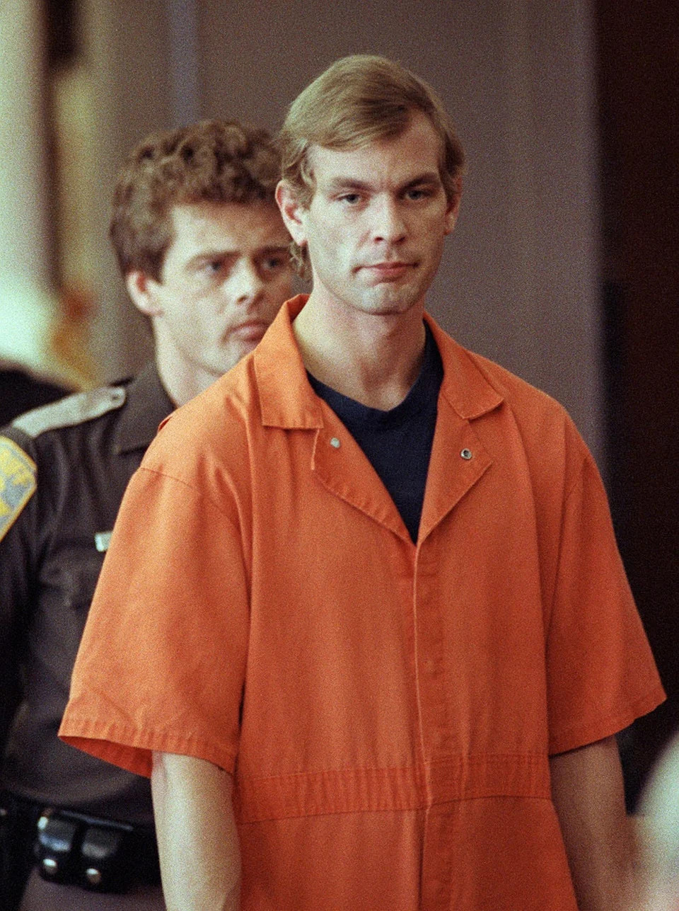 A close-up of Jeffrey Dahmer in an orange jumpsuit in court