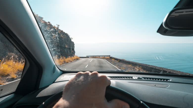 First-person perspective of a man driving on a coastal road