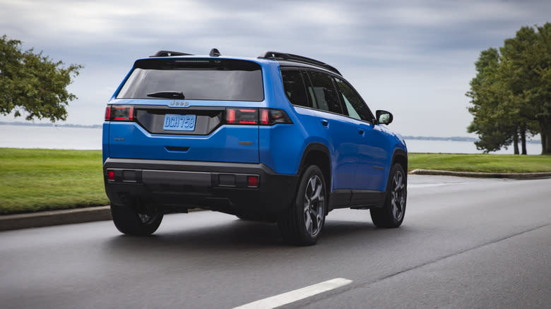 rear three quarters shot of the blue Cherokee Overland driving next to a body of water
