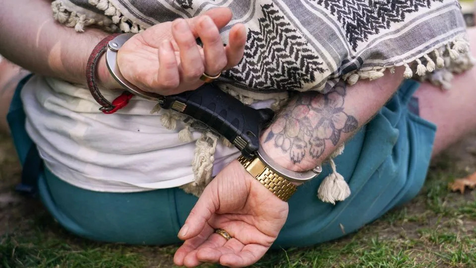 A demonstrator sits on the ground in handcuffs during the protest in London on Saturday. - Alberto Pezzali/AP