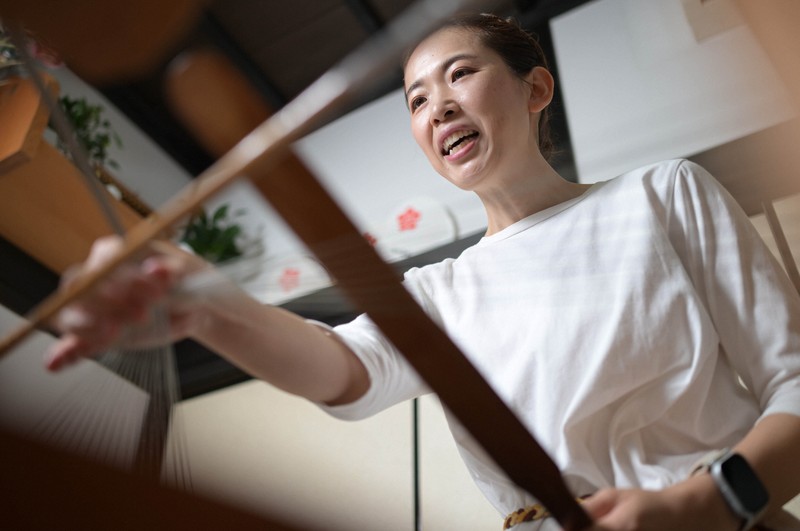 竹ベラを打ち込んで帯締めを組んでいく藤岡かほりさん＝三重県伊賀市で2025年8月21日、山崎一輝撮影