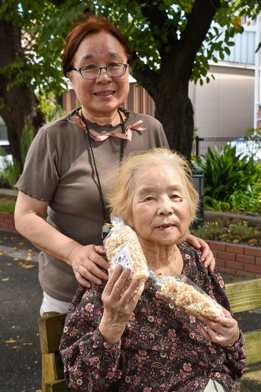 ポン菓子を手にほほ笑む吉村利子さん（手前）と長女の真貴子さん＝北九州市戸畑区で2024年9月、成松秋穂撮影