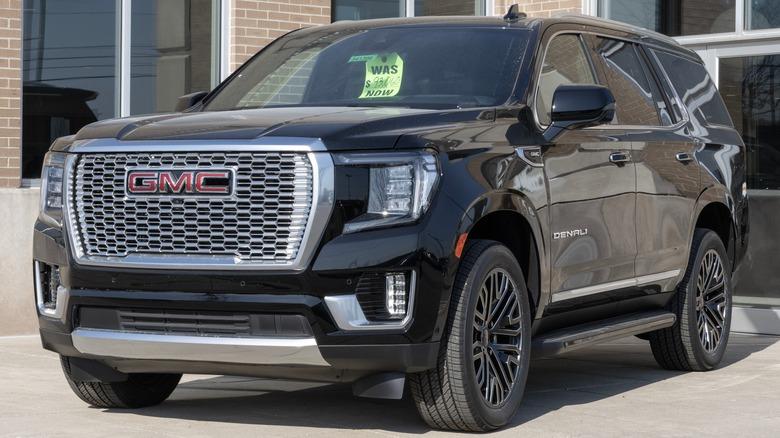 A black GMC Yukon parked in front of a building