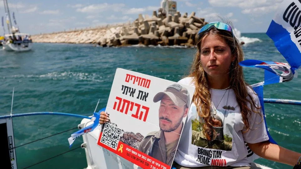 A woman holds a sign with a picture of a hostage aboard a boat heading for Gaza on Thursday. - Amir Cohen/Reuters