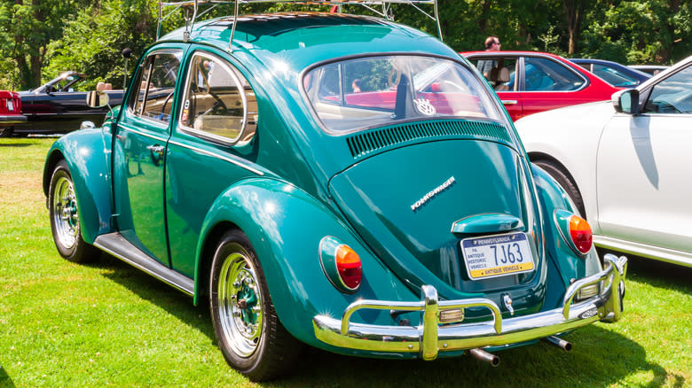 A vintage 1967 Volkswagen Beetle in blue parked on grass.