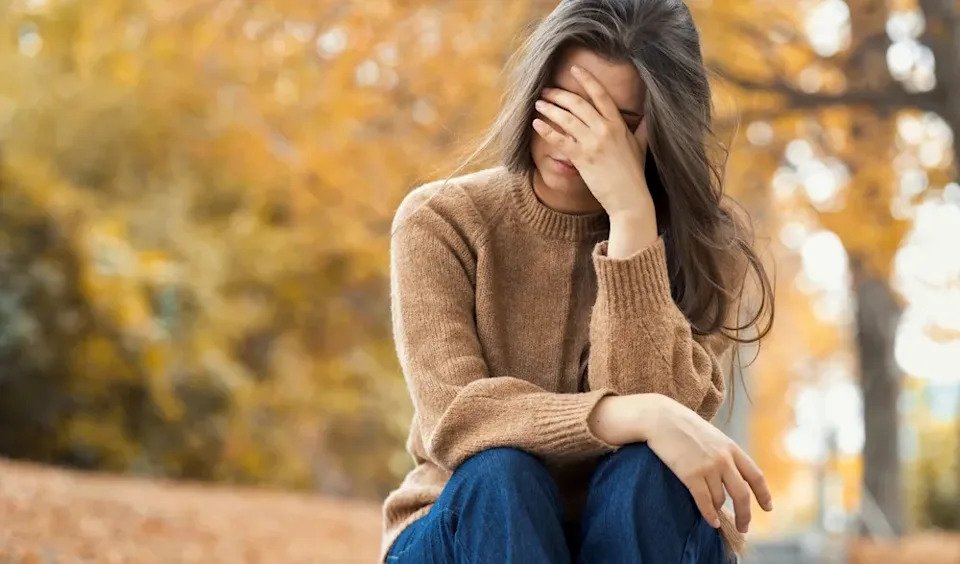 Woman upset and holding her face in her hands.