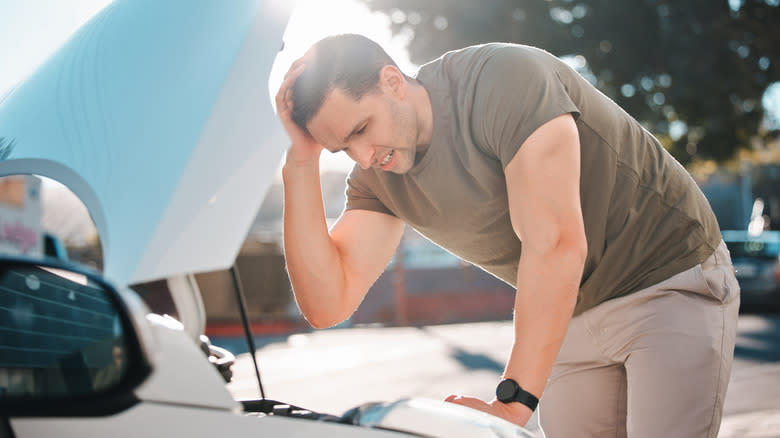 A person facing car trouble with the hood open.
