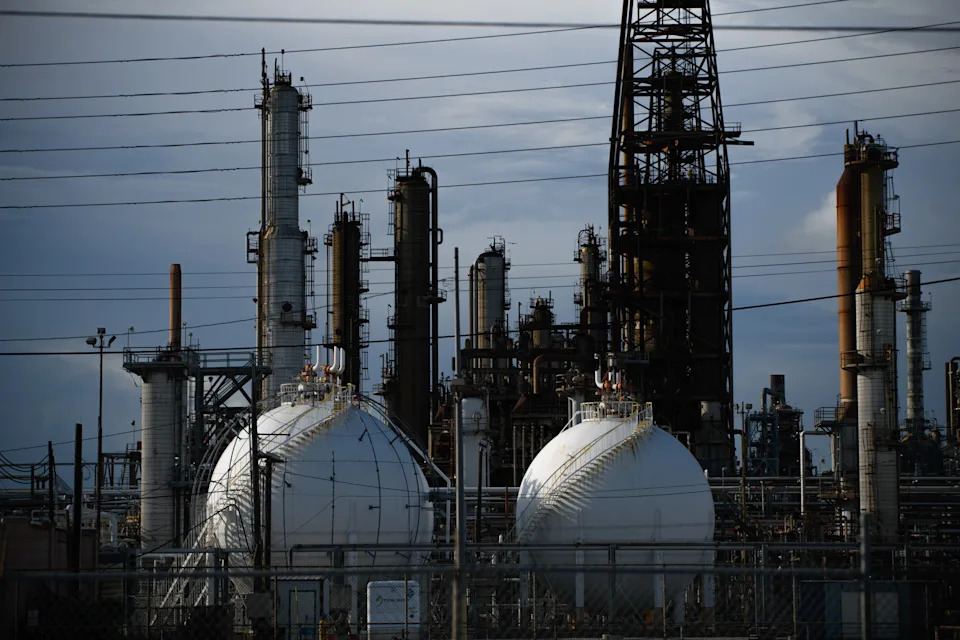 Industrial refinery with multiple towers, pipelines, and spherical storage tanks under a cloudy sky
