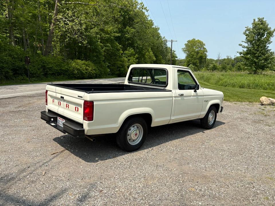 rear right angle of beige pickup truck showing tailgate, black bumper, and bed cover.