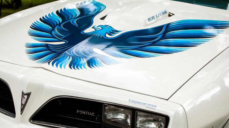 A white Pontiad Trans-Am car with bird decal on hood
