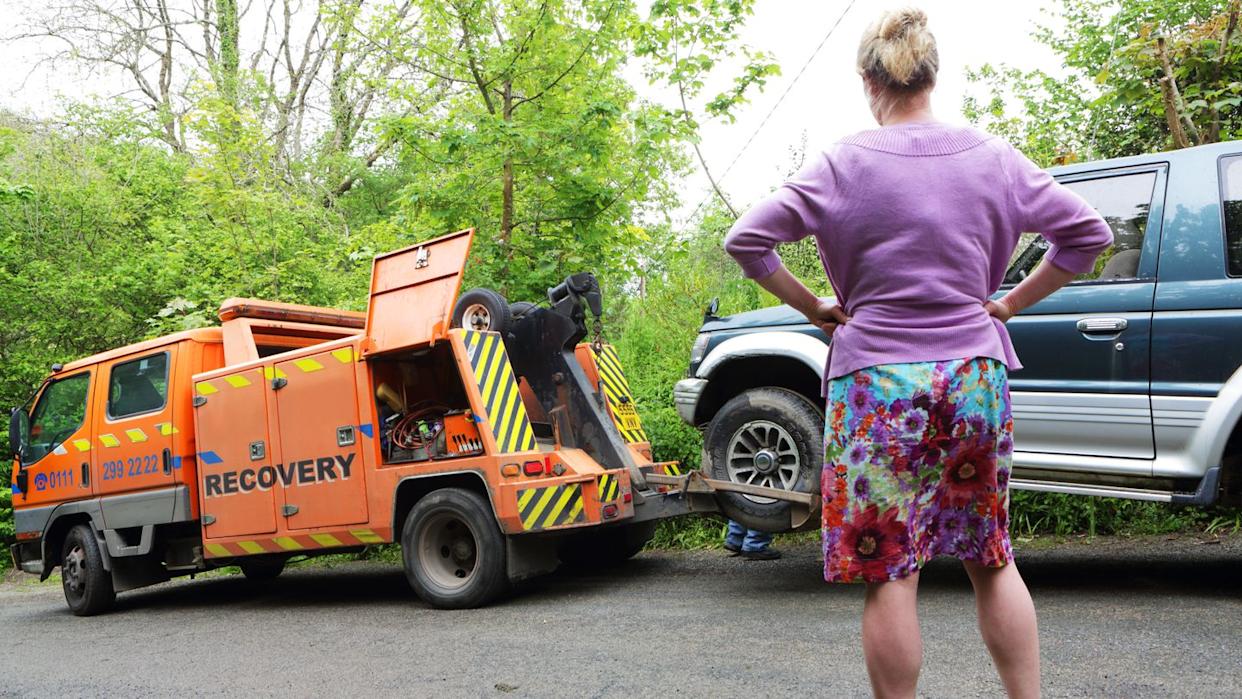 woman watching car towed away
