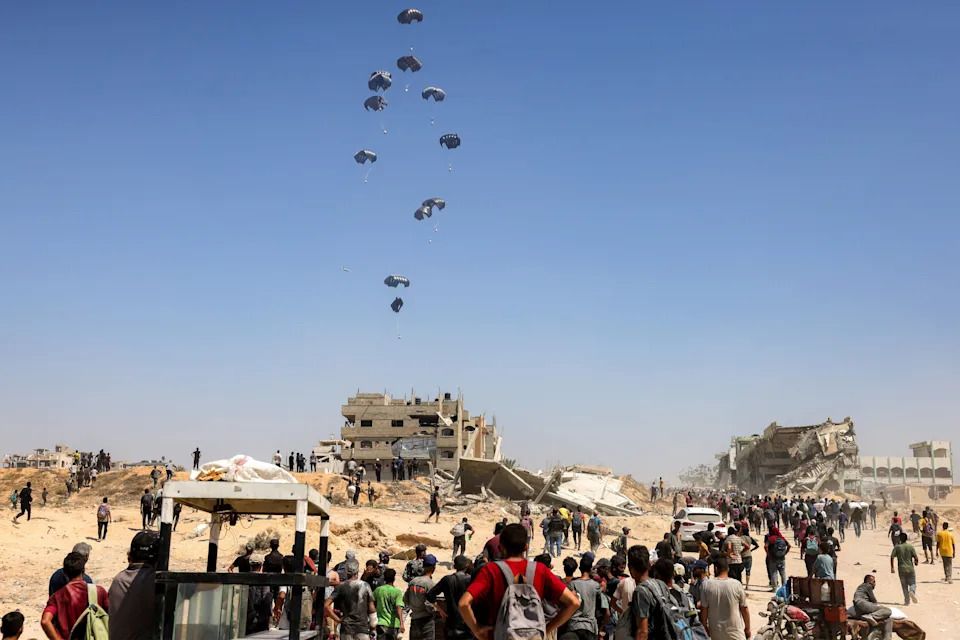 People gather as a C-130 Hercules military transport aircraft drops humanitarian aid on the northern Gaza Strip, July 27, 2025. / Credit: BASHAR TALEB/AFP/Getty