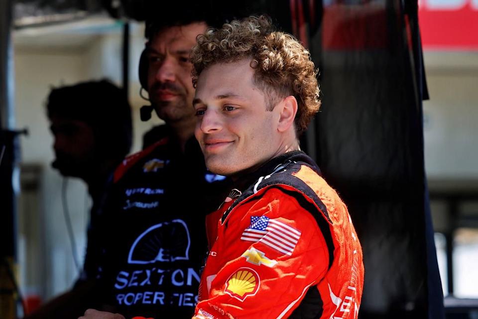 individuals in racing attire in a pit area