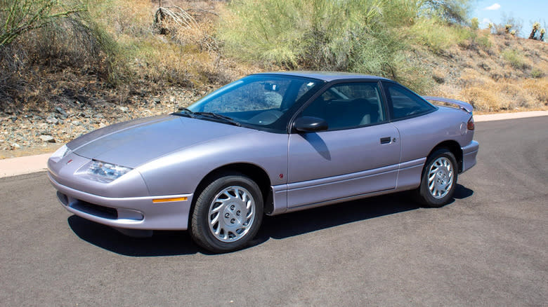 a silver Saturn SC1 coupe parked in front of plants