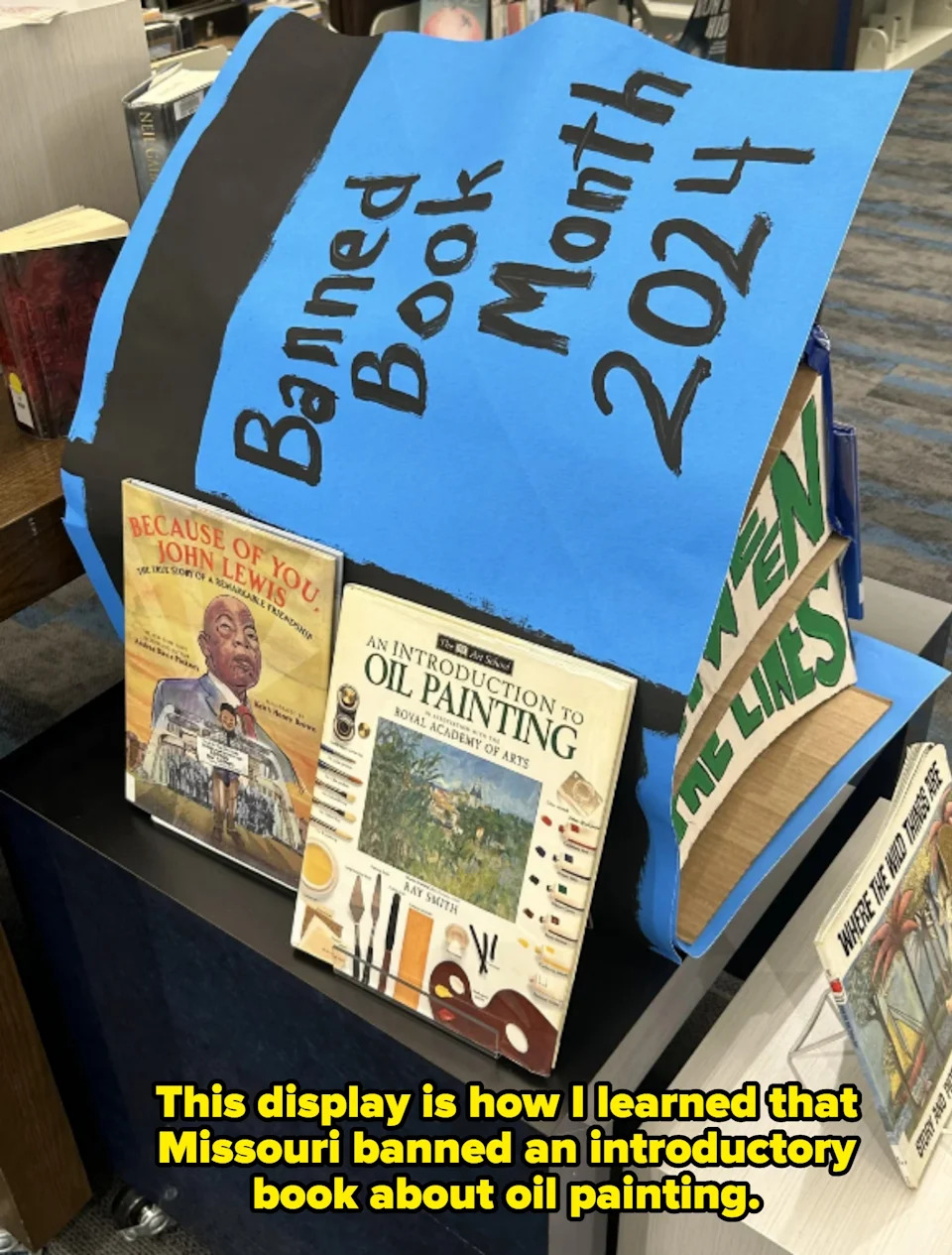 Display of various banned books with a prominent "Banned Book Month 2024" sign in a bookstore; one is an oil painting book