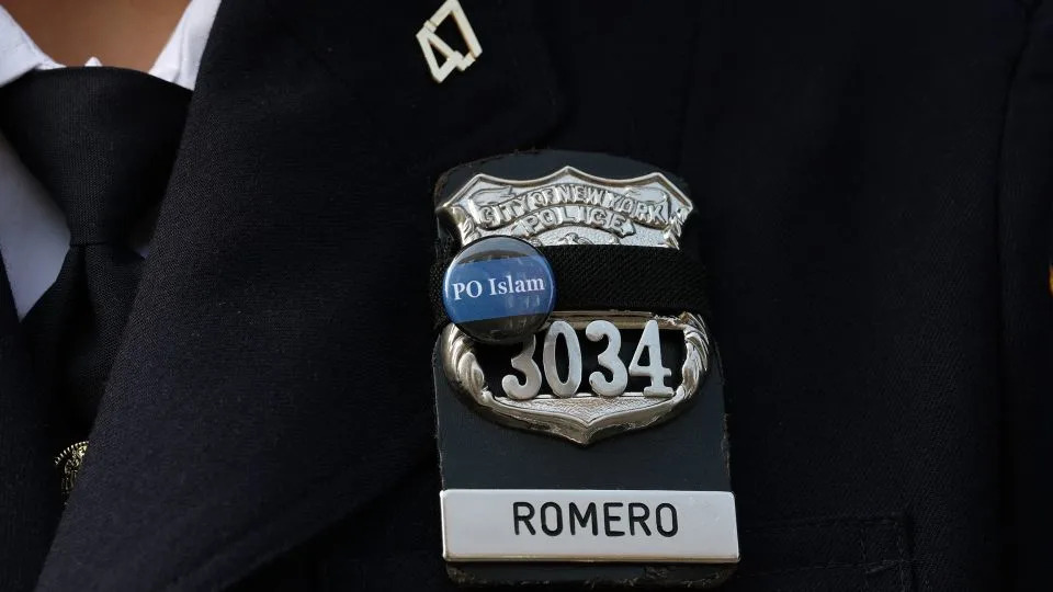 An NYPD officer wears a pin in honor of Officer Didarul Islam, who joined the department as a school safety agent in 2019 before becoming a police officer. - Timothy A. Clary/AFP/Getty Images