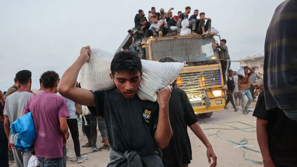 Palestinians carry aid parcels west of Beit Lahia in Gaza on July 29. - Omar al-Qatta/AFP/Getty Images/File