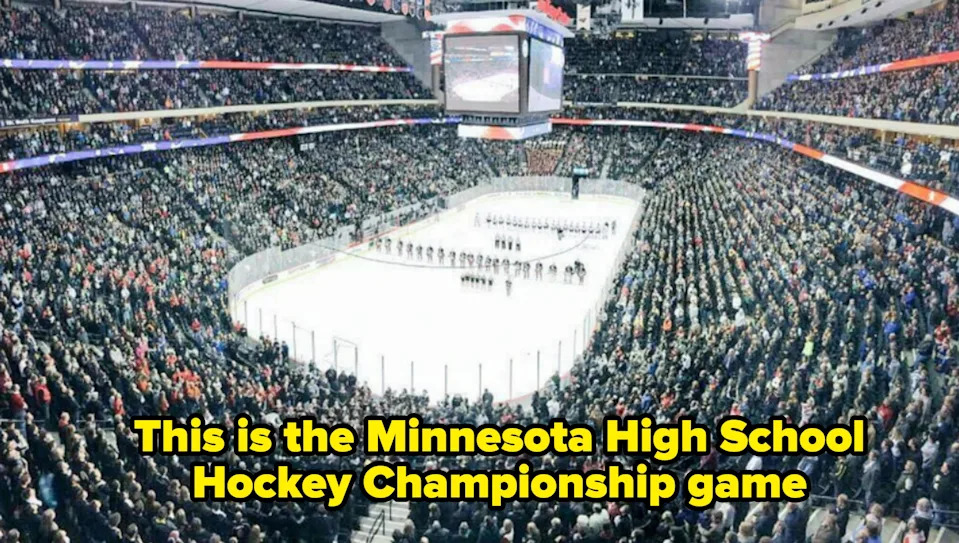 Crowded indoor arena with people watching a high school hockey game. Ice rink is in the center, and teams line up on the ice