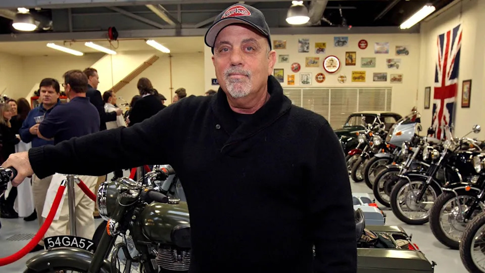 Billy Joel is pictured standing inside his motorcycle shop.