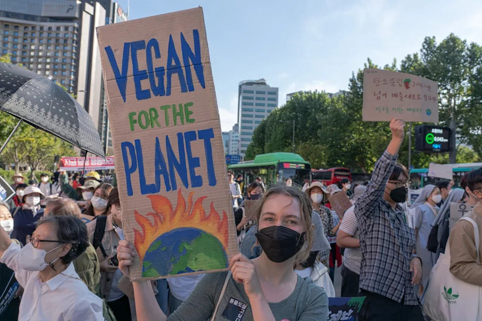 a woman in a crowd holds a hand-painted sign