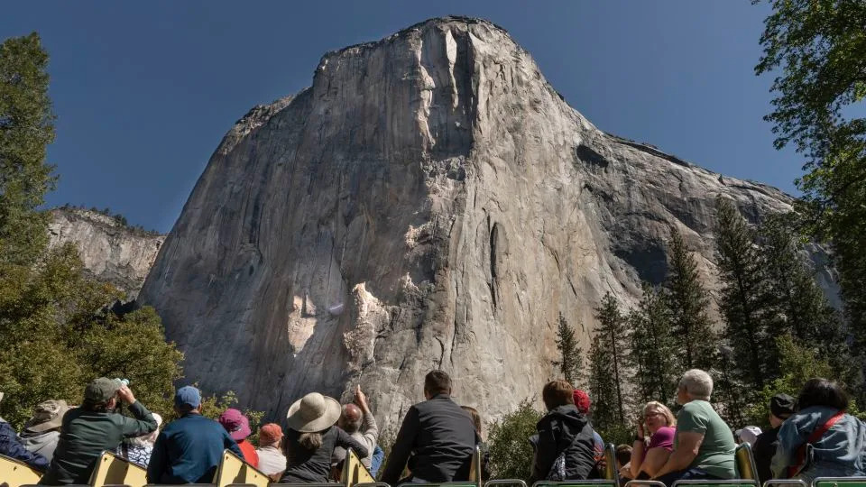 Yosemite National Park visitors view El Capitan as a transgender flag hangs from it in May. - Jayce Kolinski/AP