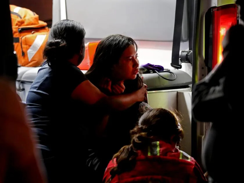 A woman holds a stunned girl.