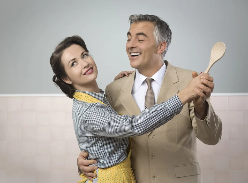 Smiling vintage couple dancing in the kitchen.