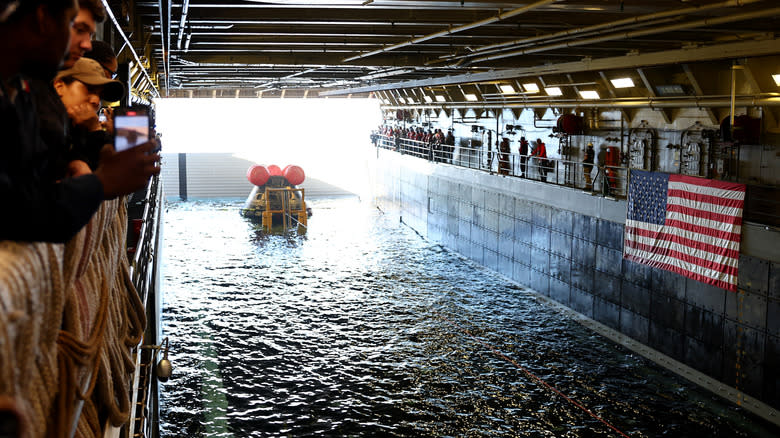 Crew members gather after NASA's Orion Capsule was brought into the well deck of the U.S.S. Portland, after it splashed down following a successful uncrewed Artemis I Moon Mission, on December 11, 2022 seen from aboard the U.S.S. Portland in the Pacific Ocean off the coast of Baja California, Mexico.