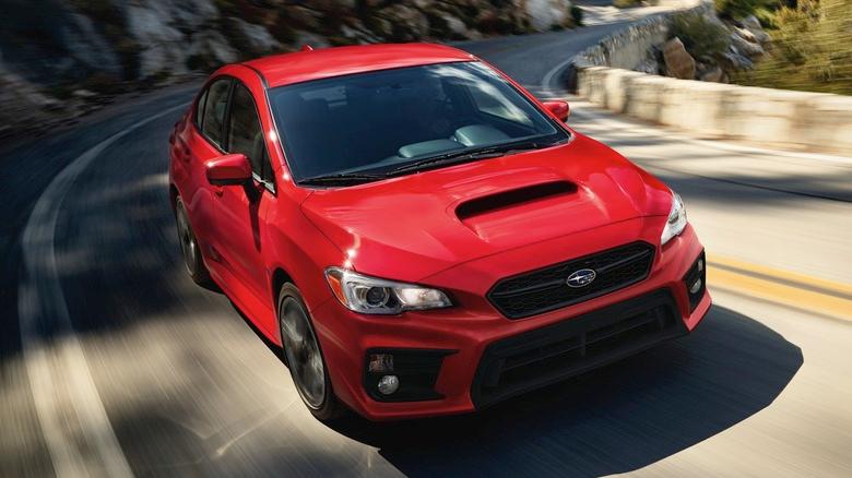 A red Subaru WRX driving through a canyon road