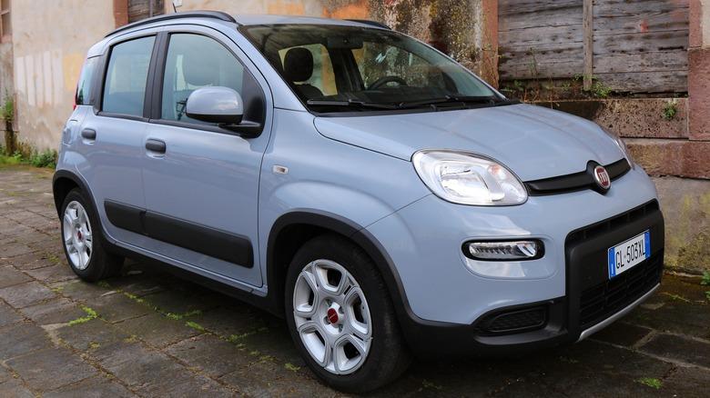A gray Fiat Panda parked next to a building