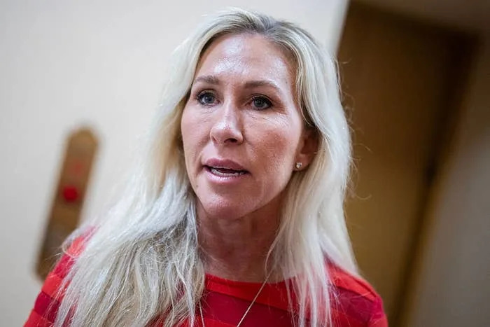 I don’t know who this person is. The image shows a woman with long blonde hair, wearing a patterned top, and looking slightly off-camera indoors