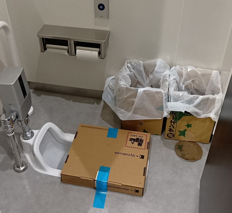 災害用トイレの隣りにある和式便器を使用中止にして設けられたし尿の集積場所。用を足した利用者がポリ袋を段ボール箱内に入れ、各階の担当課職員が1階へ運ぶ＝徳島市万代町1の徳島県庁で2025年8月7日午後1時10分、植松晃一撮影