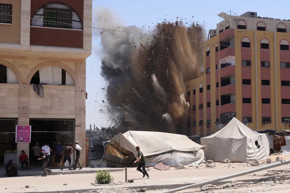 People run from a building that was just hit by an Israeli airstrike in Gaza.