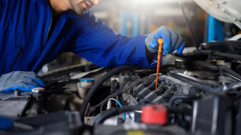 A mechanic checks the condition of oil in an engine