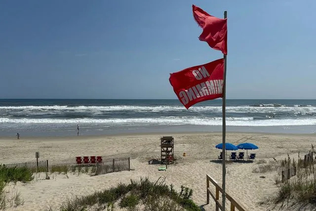 AP Photo/Pablo Martinez Monsivais Red flags, indicating swimming is prohibited, are raised at the beach in Duck, N.C., on Aug. 19, 2025.
