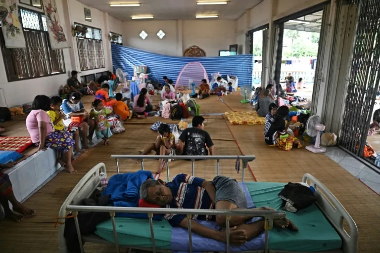 Evacuees displaced by the ongoing conflict between Thailand and Cambodia rest at a makeshift evacuation center inside a Buddhist temple in Thailand's Si Sa Ket province (Lillian SUWANRUMPHA)