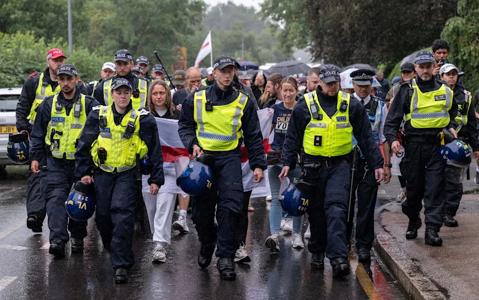 Protesters are pictured with police officers outside The Bell Hotel
