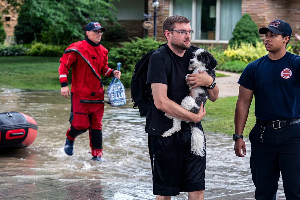A resident carries a dog in floodwaters as first responders help. (Andy Manis / Getty Images)