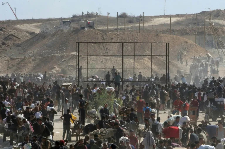 Palestinians wait to receive aid from a distribution point in the Netzarim Corridor, an Israeli military zone that cuts the Gaza Strip in two. (Eyad BABA)