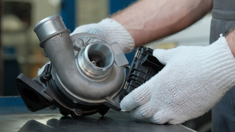 Gloved hands of a technician inspect a turbocharger on a work bench