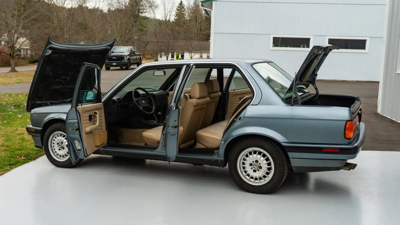 side view of a blue 1989 BMW 325i with all of its doors open, its hood open, and its trunk open.