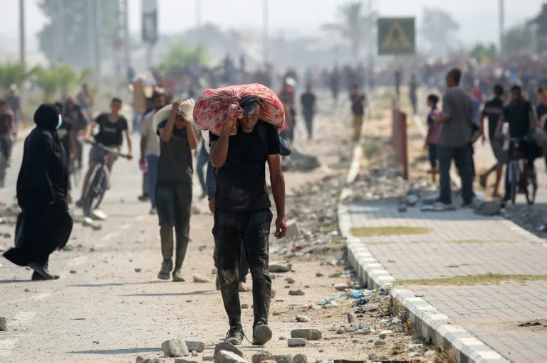 Palestinians return to Gaza's Nuseirat refugee camp with food parcels they have managed to obtain from an aid distribution point in the Israeli-controlled Netzarim Corridor. (Eyad BABA)