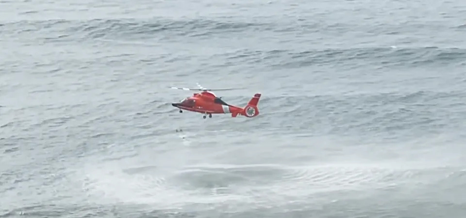 The rescue swimmer swims over to the lifeguards and the girl.