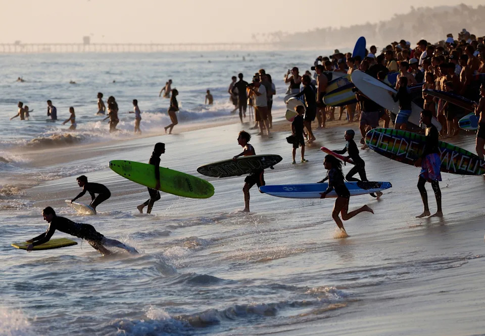 K.C. Alfred/The San Diego Union-Tribune via Getty Images - PHOTO: People run out to surf during the "Slamarack" session at Tamarack Beach on August 6, 2025 in Carlsbad, CA.