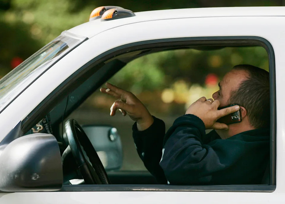 A driver talks on his phone while driving through downtown Toronto October 26, 2009. A new Ontario ban on cellphones and other hand-held devices while driving started today.