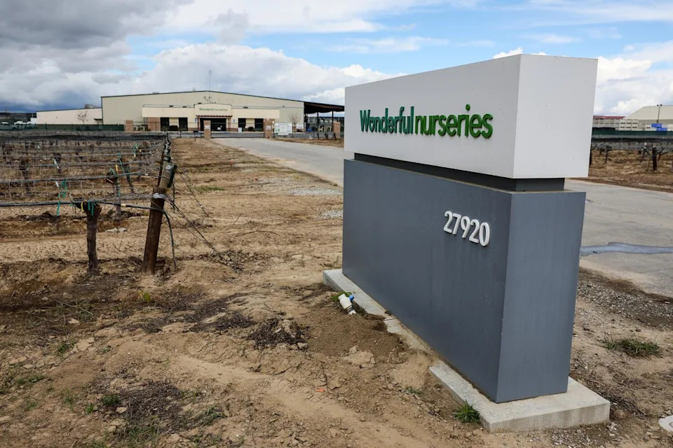 A sign that says "Wonderful nurseries" on a road that leads to a wide building.