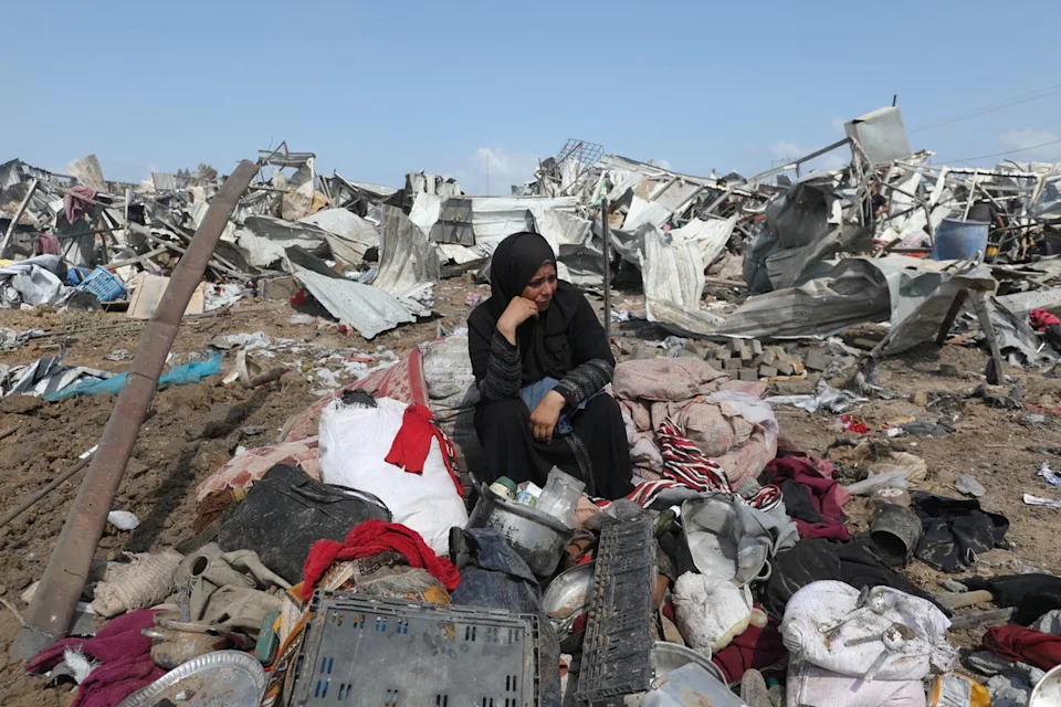 A Palestinian woman sits with her belongings after an Israeli strike on a camp for internally displaced people in Deir al-Balah, in the central Gaza Strip (AFP/Getty)