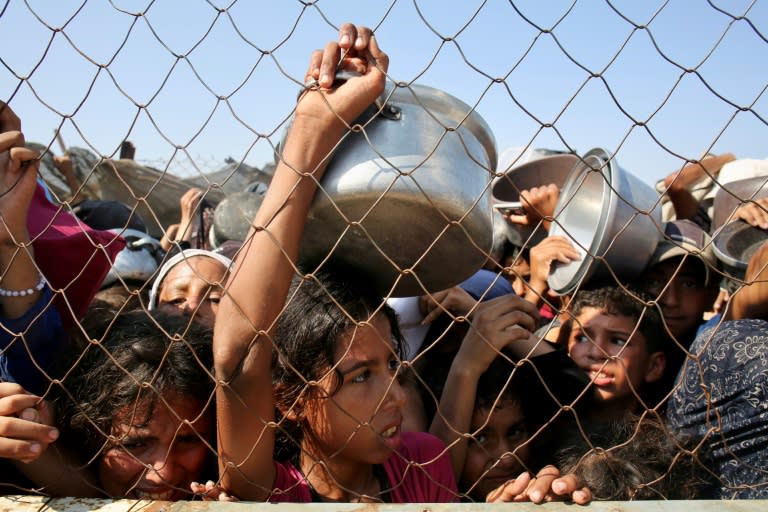Niños palestinos esperan para recibir comida en la zona de Al Mawasi, en el sur de la Franja de Gaza, el 22 de julio de 2025 (-)