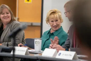  Former State Sen. Lou Ann Linehan of the Elkhorn area, center, motions to Superintendent John Schwartz of Millard Public Schools during the first meeting of the School Financing Review Commission. To Linehan’s right is Nebraska Property Tax Administrator Sarah Scott. Aug. 12, 2025. (Zach Wendling/Nebraska Examiner)